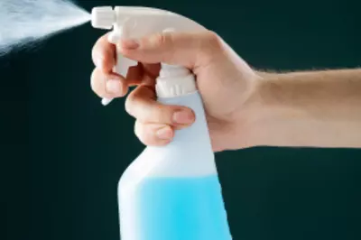 Hand spraying a bottle of cleaning solvent.
