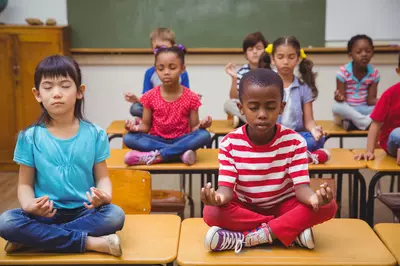 kids sitting cross legged in a class room