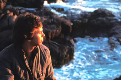 person looking over rocky shore at waves