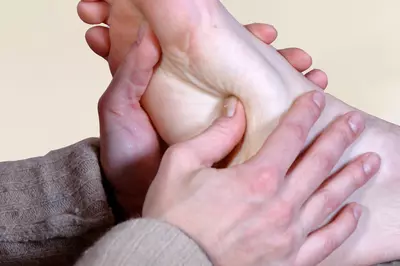 relexologist applying pressure to the foot
