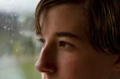 man looking sad out rainy window