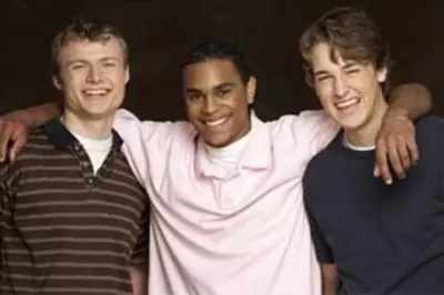 Three smiling teen friends with arms around each other