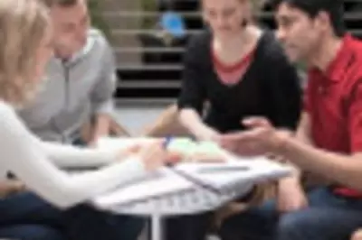 Group of coworkers sit at table and look at notes together