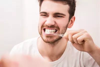 Man brushing his teeth and looking in the mirror