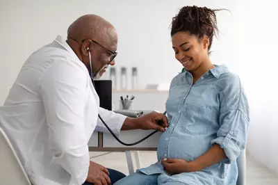 doctor listening to baby's heartbeat in pregnant woman's stomach