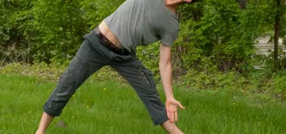 person doing yoga outside in a green park