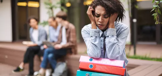 African American woman sitting away from peers looking stressed