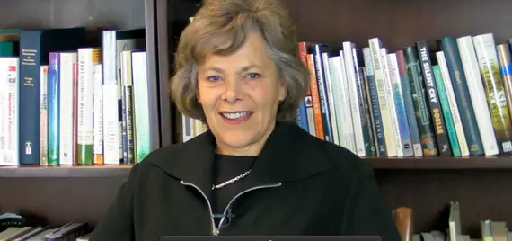 Ellen Langer smiling in front of a bookshelf