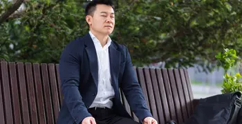 person in suit breathing on a bench outside