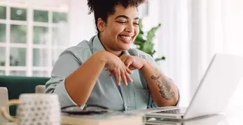 Woman video calling using laptop at home 