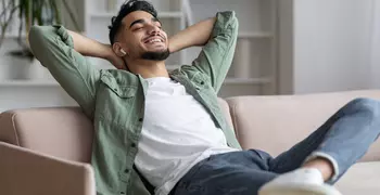 man relaxing on the couch with airpods