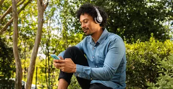 man sitting in the forest on his phone