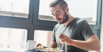 man eating breakfast by a window