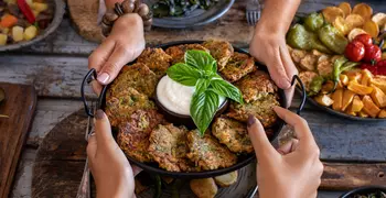 two people holding a bowl of vegetable fritters