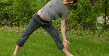 person doing yoga outside in a green park