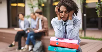 African American woman sitting away from peers looking stressed