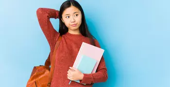 student holding books and bag looking pensive and uncertain