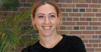 Kelly Mcgonical smiling at the camera in front of a brick wall