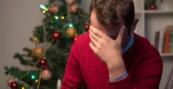 person holding their head in their hands in a red sweater