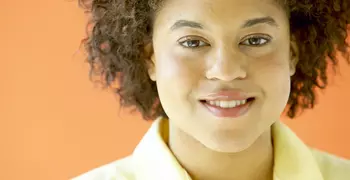 person smiling at the camera in a yellow button up.