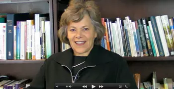 Ellen Langer smiling in front of a bookshelf