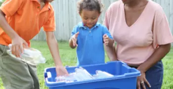 Three people, two adults and one child, recycling plastic 