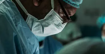close up of a surgeon in scrubs and mask looking down at a patient