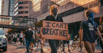 people marching in the streets, one carrying a sign that says I Can't Breathe