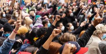 fists raised in solidarity at an outdoor protest