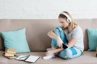 girl sitting on couch listening to headphones