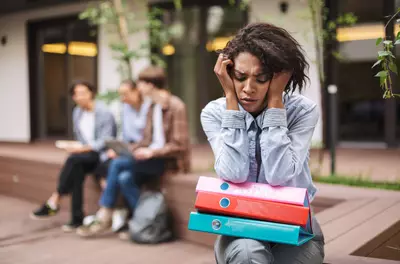 African American woman looking sad sitting away from peers