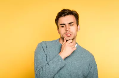 doubtful man looking downwards against yellow background