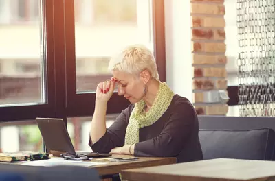 woman looking stressed sitting at table in front of computer