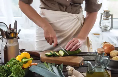 hands cutting a zucchini in a kitchen