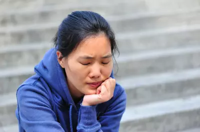 stressed woman sitting on the steps of a building with her chin in her hand