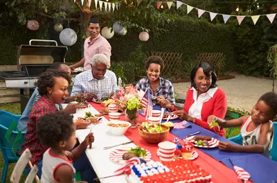 multigenerational family sitting around a picnic table eating dinner and laughing