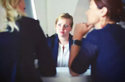 woman listening to two others speak in a meeting