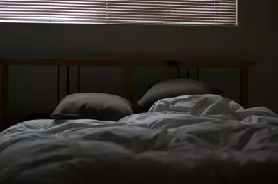 rumpled bed in a dark and cozy bedroom