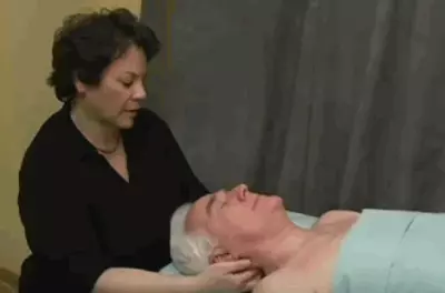masseuse holding client's head as he lies on table