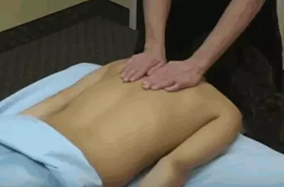 masseuse's hands pressing on a client's bare back