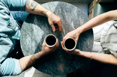 birds-eye view of two people with coffee cups at a small table