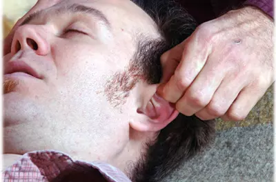 close up of man getting ear reflexology while he sleeps
