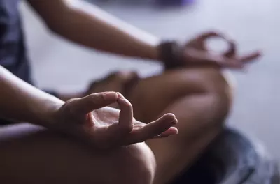 close up of hands in meditation, with thumbs and index fingers touching in a circle
