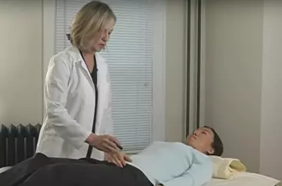 healthcare practitioner standing next to a woman lying on a table