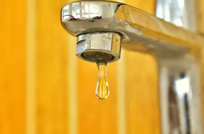 closeup of sink faucet with drip coming out