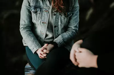 two people sitting next to one another, their hands on their laps