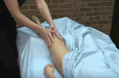masseuse's hands rubbing a client's bare knee