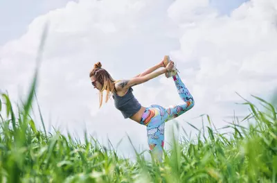 woman with colorful exercise pants stretching outside in the grass
