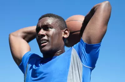 black male basketball player with the ball behind his head