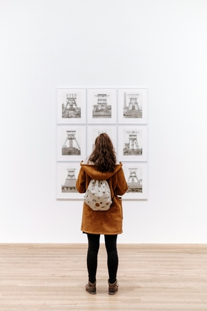 back of woman as she looks at a painting in an art museum